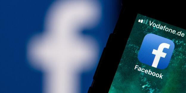 Ein Smartphone mit Facebook-Logo auf dem Bildschirm liegt auf einem Laptop Ein Smartphone mit Facebook-Logo auf dem Bildschirm liegt auf einem Laptop