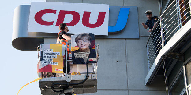 Ein Demonstrant bringt ein Logo der CDU mit einer Hebebühne an der CSU-Zentrale an. Ein Demonstrant bringt ein Logo der CDU mit einer Hebebühne an der CSU-Zentrale an.