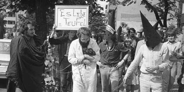 Fritz Teufel hält einen Strauß Nelken im Arm, um ihn herum Demonstranten Fritz Teufel hält einen Strauß Nelken im Arm, um ihn herum Demonstranten