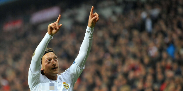 Mesut Özil steht auf dem Platz streckt beide Zeigefinger in die Luft Mesut Özil steht auf dem Platz streckt beide Zeigefinger in die Luft