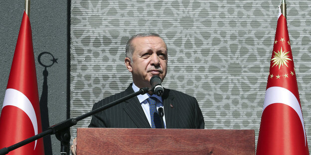 Recep Tayyip Erdogan steht an einem Stehpult, zwischen zwei türkischen Fahnen Recep Tayyip Erdogan steht an einem Stehpult, zwischen zwei türkischen Fahnen