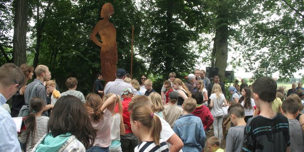 Viele Schulkinder stehen vor der Silhouette einer Frau – es ist ein Denkmal für Jutta Bamwoll, die im KZ ermodert wurde Viele Schulkinder stehen vor der Silhouette einer Frau – es ist ein Denkmal für Jutta Bamwoll, die im KZ ermodert wurde