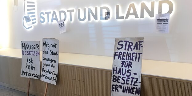 Ein Wand mit der Beschriftung "Stadt und Land" und mehreren Protestplakaten