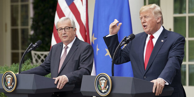 EU-Kommissionspräsident Juncker und US-Präsident Trump stehen an Pulten vor dem Weißen Haus, Trump redet und hat den linken Arm erhoben EU-Kommissionspräsident Juncker und US-Präsident Trump stehen an Pulten vor dem Weißen Haus, Trump redet und hat den linken Arm erhoben