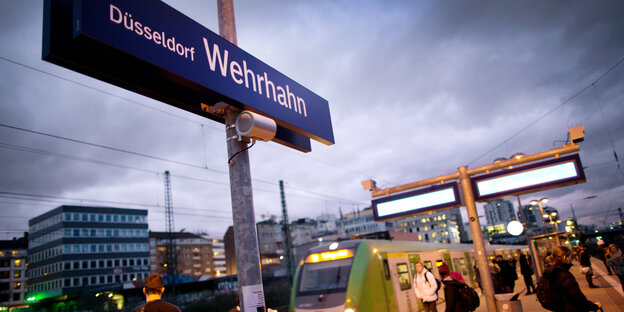 Ein Bahnhofsteig mit einem Schild auf dem "Düsseldorf Wehrhahn" steht Ein Bahnhofsteig mit einem Schild auf dem "Düsseldorf Wehrhahn" steht