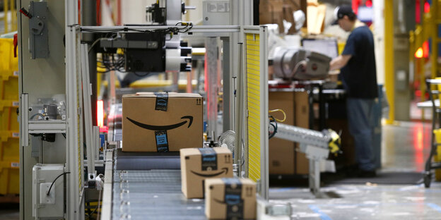 Amazon-Pakete auf einem Fließband unter einem Scanner Amazon-Pakete auf einem Fließband unter einem Scanner