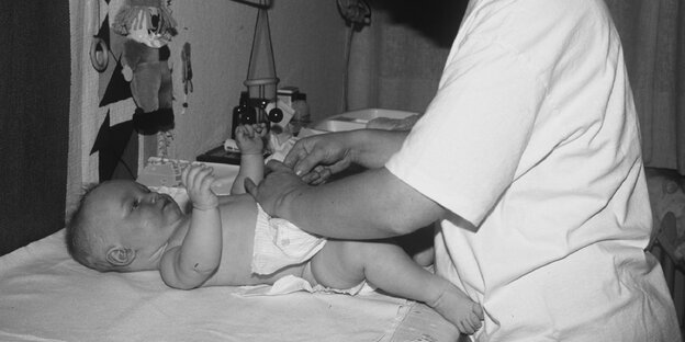 Eine Mutter wickelt ihr Baby mit einer Einwegwindel Eine Mutter wickelt ihr Baby mit einer Einwegwindel