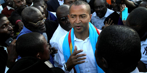 Moise Katumbi steht gestikulierend zwischen anderen Menschen Moise Katumbi steht gestikulierend zwischen anderen Menschen