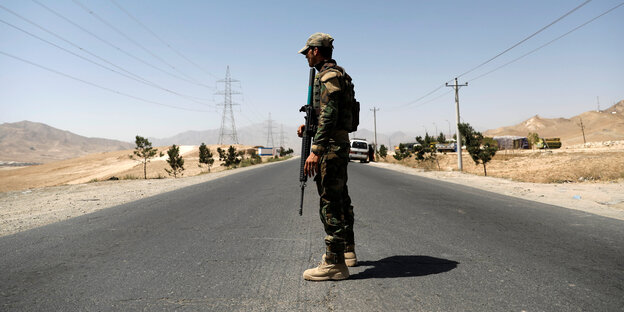 Ein afghanischer Soldat überwacht einen Checkpoint an der Straße Ein afghanischer Soldat überwacht einen Checkpoint an der Straße