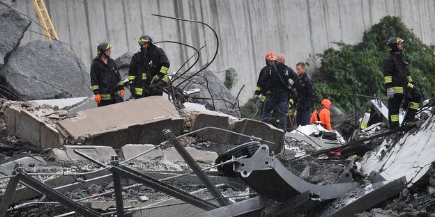 Rettungskräfte stehen in den Trümmern der Brücke Rettungskräfte stehen in den Trümmern der Brücke