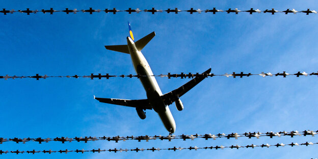 Ein Flugzeug fliegt über Reihen von Stacheldraht Ein Flugzeug fliegt über Reihen von Stacheldraht