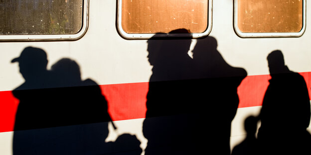Vor einem Zug spiegeln sich die Schatten von Menschen Vor einem Zug spiegeln sich die Schatten von Menschen
