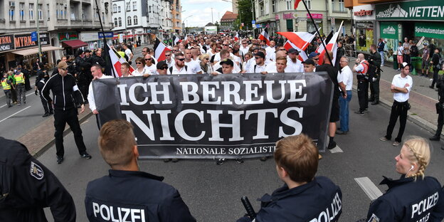 Neonazis stehen hinter einem Plakat mit der Aufschrift "Ich bereue nichts" Neonazis stehen hinter einem Plakat mit der Aufschrift "Ich bereue nichts"