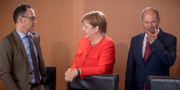 Heiko Maas und Olaf Scholz, der sich die Mundwinkel nach oben zieht,Merkel in der Mitte Heiko Maas und Olaf Scholz, der sich die Mundwinkel nach oben zieht,Merkel in der Mitte