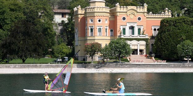 Vor einer Luxusvilla zwei Wassersportler Vor einer Luxusvilla zwei Wassersportler