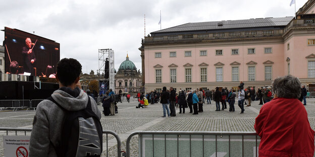 St-Hedwigskathedrale mit Zaun im Vordergrund, Leute sind angelehnt an den Zaun