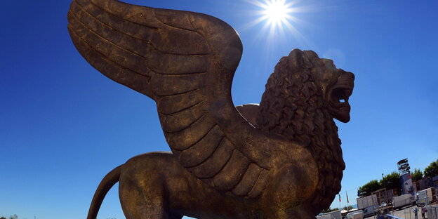 Der Löwe als Statue, dahinter blauer Himmel und Sonne Der Löwe als Statue, dahinter blauer Himmel und Sonne
