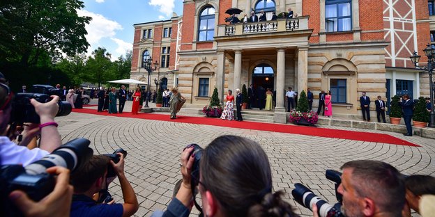 Eingangsportal des Bayreuther Festspielhauses - im Vordergrund Fotografen, die ihre Kameras auf den Eingang gerichtet haben Eingangsportal des Bayreuther Festspielhauses - im Vordergrund Fotografen, die ihre Kameras auf den Eingang gerichtet haben
