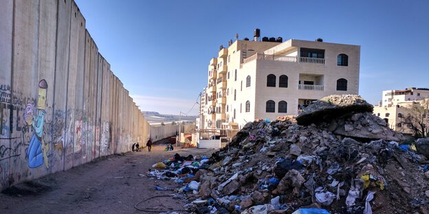 Die israelische Trennmauer vor blauben Himmer, im Hintergrund Gebäude, im Vordergrund ein Müllberg. Die israelische Trennmauer vor blauben Himmer, im Hintergrund Gebäude, im Vordergrund ein Müllberg.