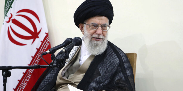 Ajatollah Ali Chamenei vor Iranflagge und Mikrofon Ajatollah Ali Chamenei vor Iranflagge und Mikrofon