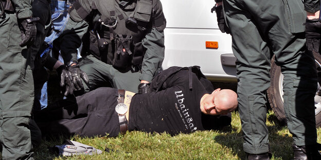 Ein Mann wird von mehreren Polizisten am Boden fixiert Ein Mann wird von mehreren Polizisten am Boden fixiert