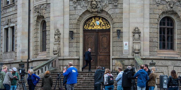 Eine Gruppe von Menschen mit Kameras steht auf einem großen Gebäude mit pompöser Tür Eine Gruppe von Menschen mit Kameras steht auf einem großen Gebäude mit pompöser Tür