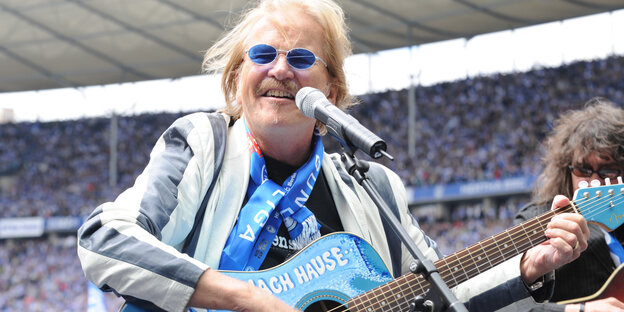 Frank Zander mit blauer Sonnenbrille, Hertha-Schal und blauer Gitarre im Stadion Frank Zander mit blauer Sonnenbrille, Hertha-Schal und blauer Gitarre im Stadion