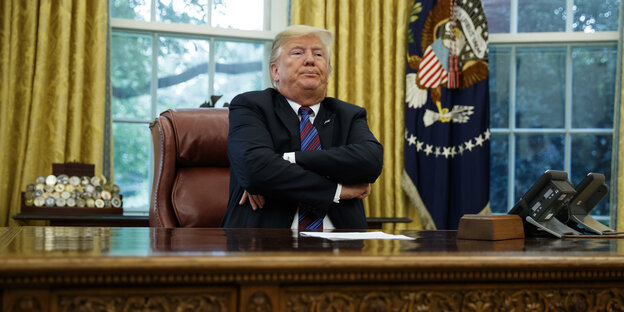 Donald Trump mit verschränkten Armen am Schreibtisch im Oval Office Donald Trump mit verschränkten Armen am Schreibtisch im Oval Office