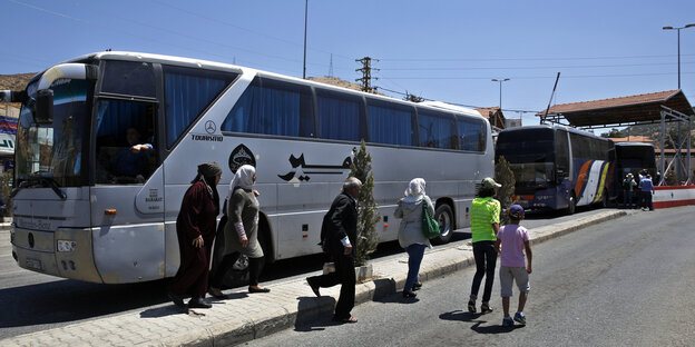 Ein Reisebus, davor mehrere Personen. Ein Reisebus, davor mehrere Personen.