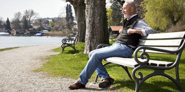 Ein älterer Herr sitzt auf einer Parkbank Ein älterer Herr sitzt auf einer Parkbank