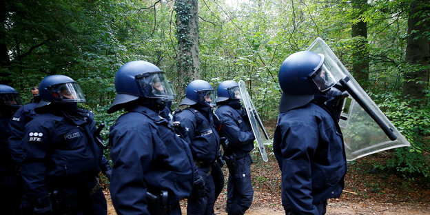 Polizisten stehen vor Bäumen in einem Wald Polizisten stehen vor Bäumen in einem Wald