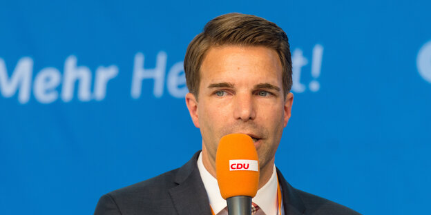 Jörg Nigge spricht in ein Mikrophon. Jörg Nigge spricht in ein Mikrophon.