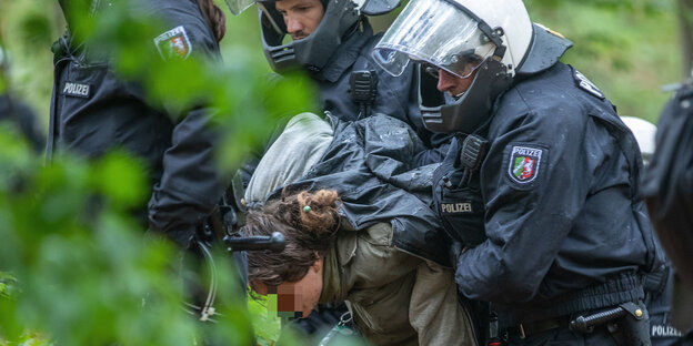 Eine junge Frau wird im Hambacher Forst mit auf dem Rücken verschränkten Armen von mehreren Polizisten abgeführt Eine junge Frau wird im Hambacher Forst mit auf dem Rücken verschränkten Armen von mehreren Polizisten abgeführt