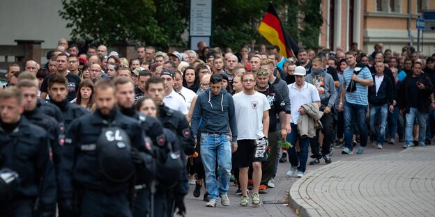 Menschen maschieren hinter Polizisten Menschen maschieren hinter Polizisten