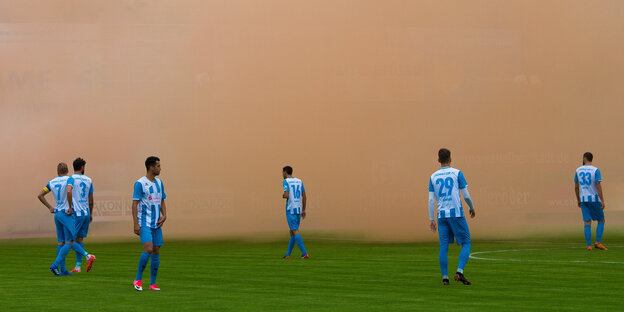 Fußballspieler im Pyro-Rauch Fußballspieler im Pyro-Rauch