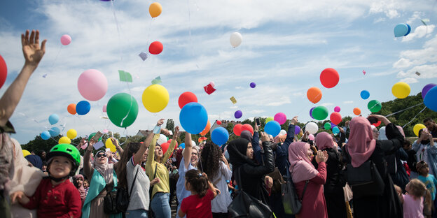 Frauen mit und ohne Kopftuch lassen Luftballons steigen Frauen mit und ohne Kopftuch lassen Luftballons steigen