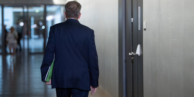 Hans-Georg Maaßen, bis Dienstag Verfassungsschutzchef, ist von hinten zu sehen. Er geht einen grauen Gang entlang an einem Fahrstuhl vorbei Hans-Georg Maaßen, bis Dienstag Verfassungsschutzchef, ist von hinten zu sehen. Er geht einen grauen Gang entlang an einem Fahrstuhl vorbei