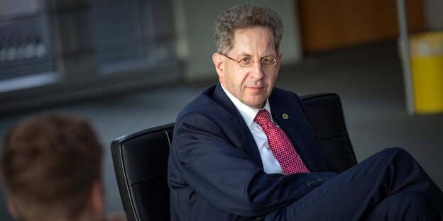 Hans-Georg Maaßen sitzt in einem Sessel und lächelt