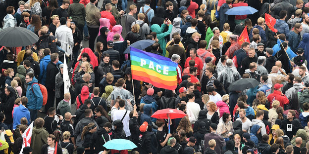 Viele Menschen demonstrieren auf der Straße in Chemnitz gegen Rassismus, in der Mitte ist eine große Regenbogenflagge, auf der Pace steht Viele Menschen demonstrieren auf der Straße in Chemnitz gegen Rassismus, in der Mitte ist eine große Regenbogenflagge, auf der Pace steht