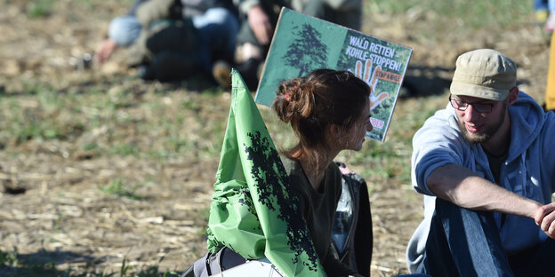 Mann und Frau mit Protestschildern auf Wiese Mann und Frau mit Protestschildern auf Wiese