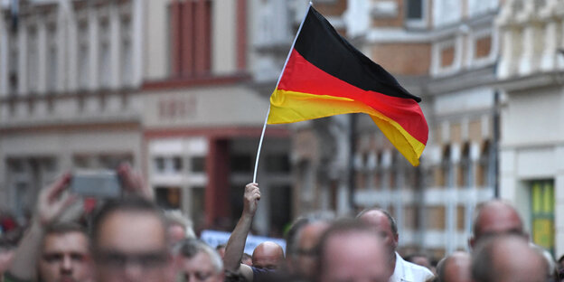 Mehrere Menschen protestieren auf einer Straße, eine Deutschlandflagge wird hochgehalten Mehrere Menschen protestieren auf einer Straße, eine Deutschlandflagge wird hochgehalten