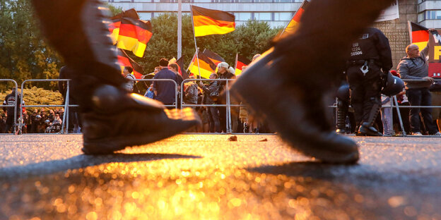 Stiefel marschieren, im Hintergrund Deutschlandflaggen Stiefel marschieren, im Hintergrund Deutschlandflaggen