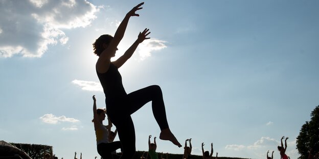 Silhouetten von Menschen, die eine Yoga-Übung im Stehen machen Silhouetten von Menschen, die eine Yoga-Übung im Stehen machen