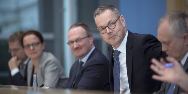 Fünf Menschen sitzen an einem Tisch Fünf Menschen sitzen an einem Tisch