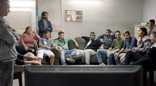Eine Gruppe Jugendlicher sitzt auf einer Couch vor einem Fernseher. Eine Gruppe Jugendlicher sitzt auf einer Couch vor einem Fernseher.