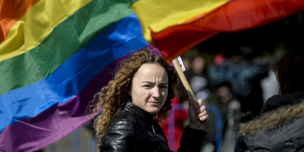 Eine Frau schwenkt eine Regenbogenfahne Eine Frau schwenkt eine Regenbogenfahne