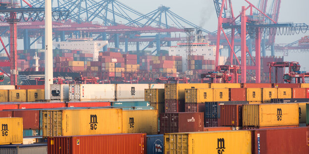 An einem Hafen stapeln sich Container, dahinter Kräne An einem Hafen stapeln sich Container, dahinter Kräne