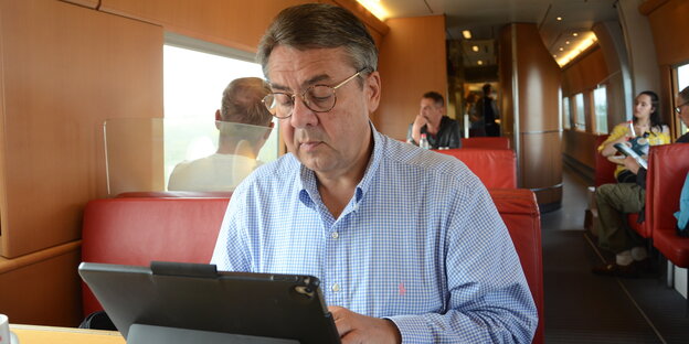 Sigmar Gabriel sitzt an seinem Tablet im Zug Sigmar Gabriel sitzt an seinem Tablet im Zug