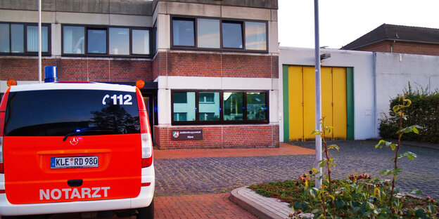 Ein rotes Notarzt-Auto steht vor einem Backsteingebäude Ein rotes Notarzt-Auto steht vor einem Backsteingebäude