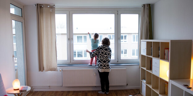 Eine Frau und ein kleines Mädchen blicken aus einem Fenster. Eine Frau und ein kleines Mädchen blicken aus einem Fenster.